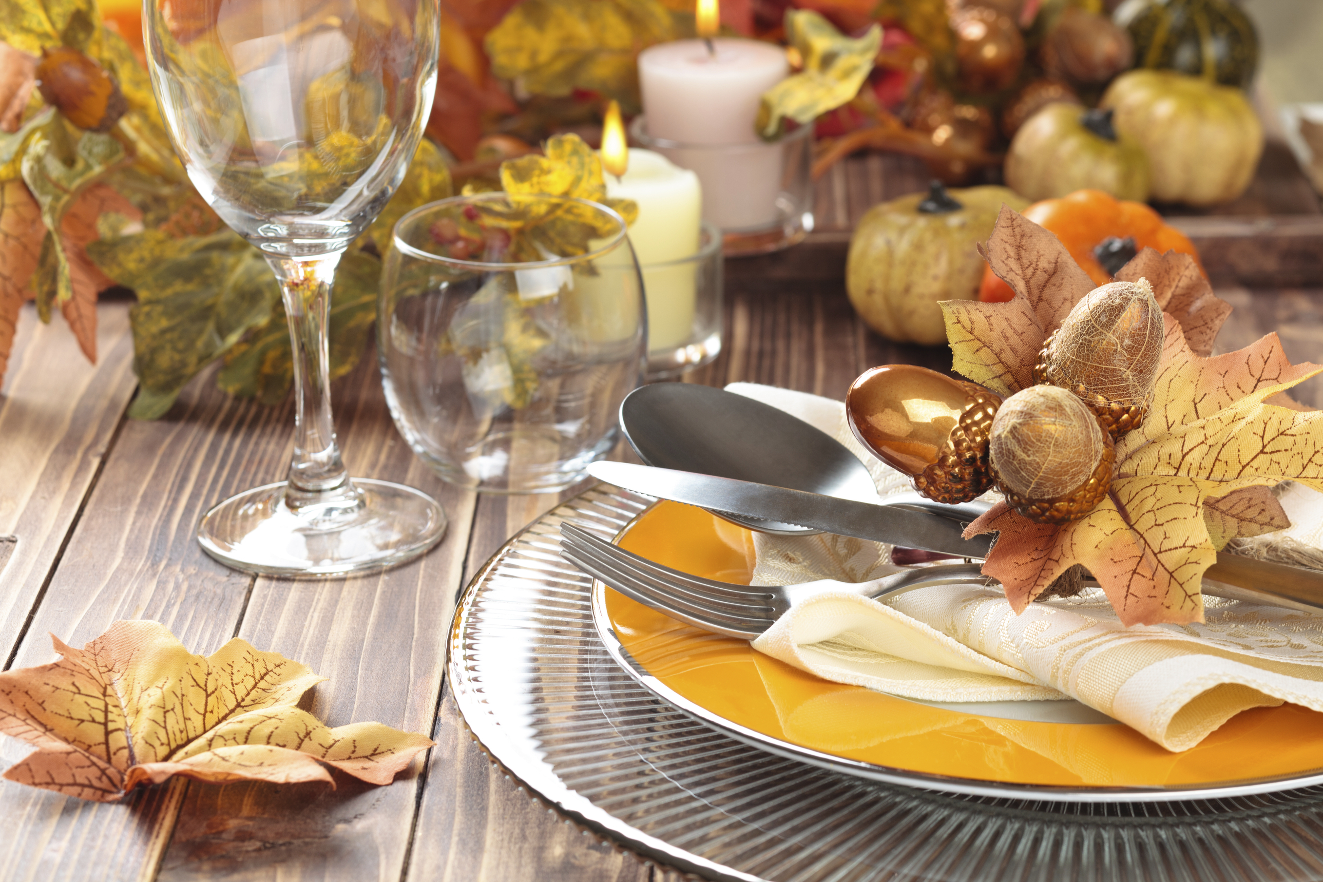 Autumn place setting with leaves, candles, and pumpkin.