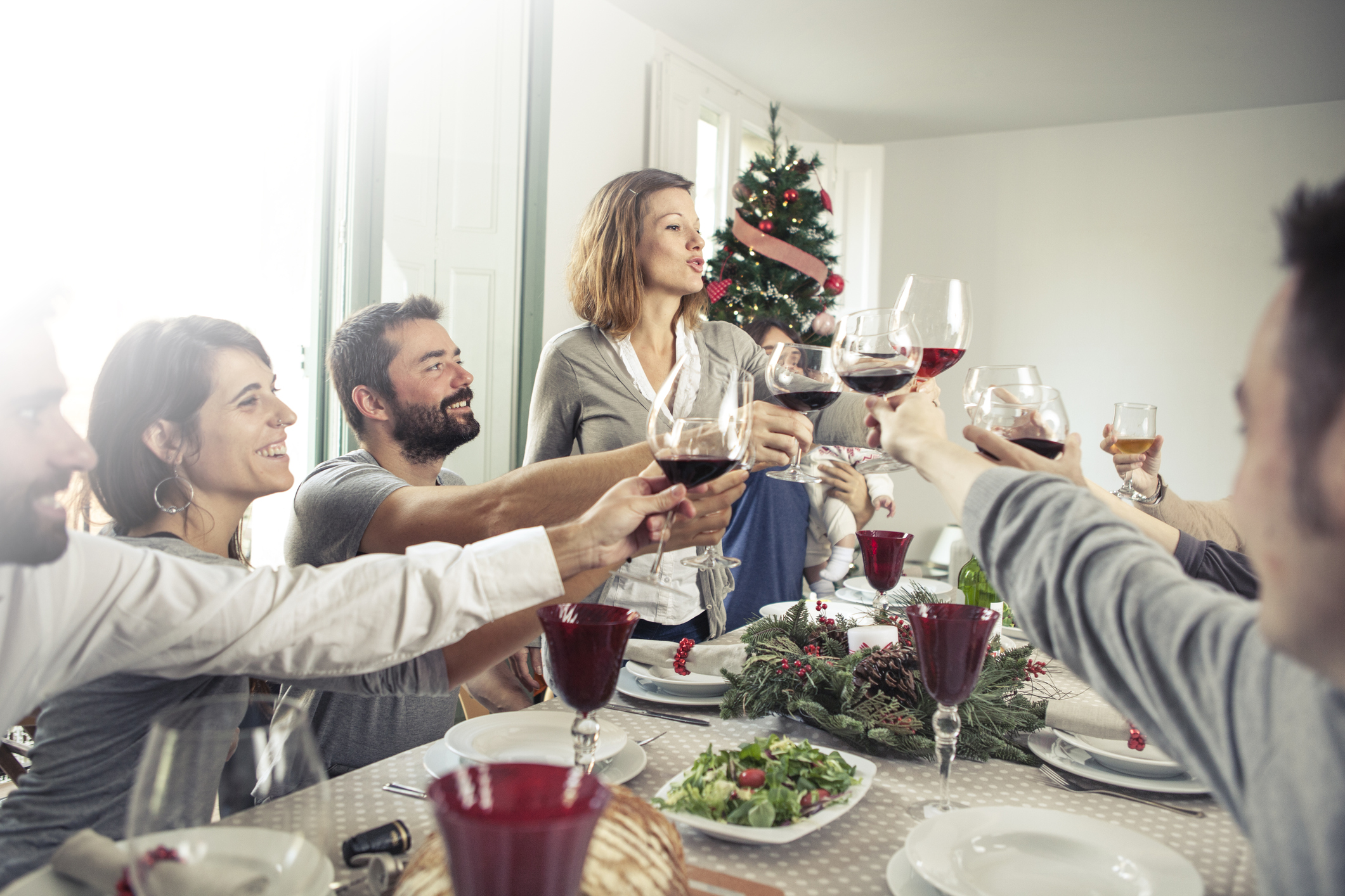 Friends toasting at a Christmas dinner around the table.