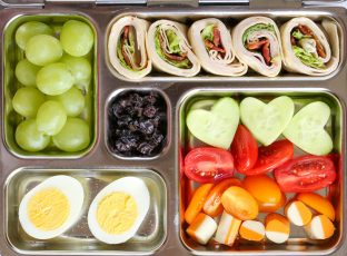 Bento box lunch with fresh fruit and turkey and cheese roll up.